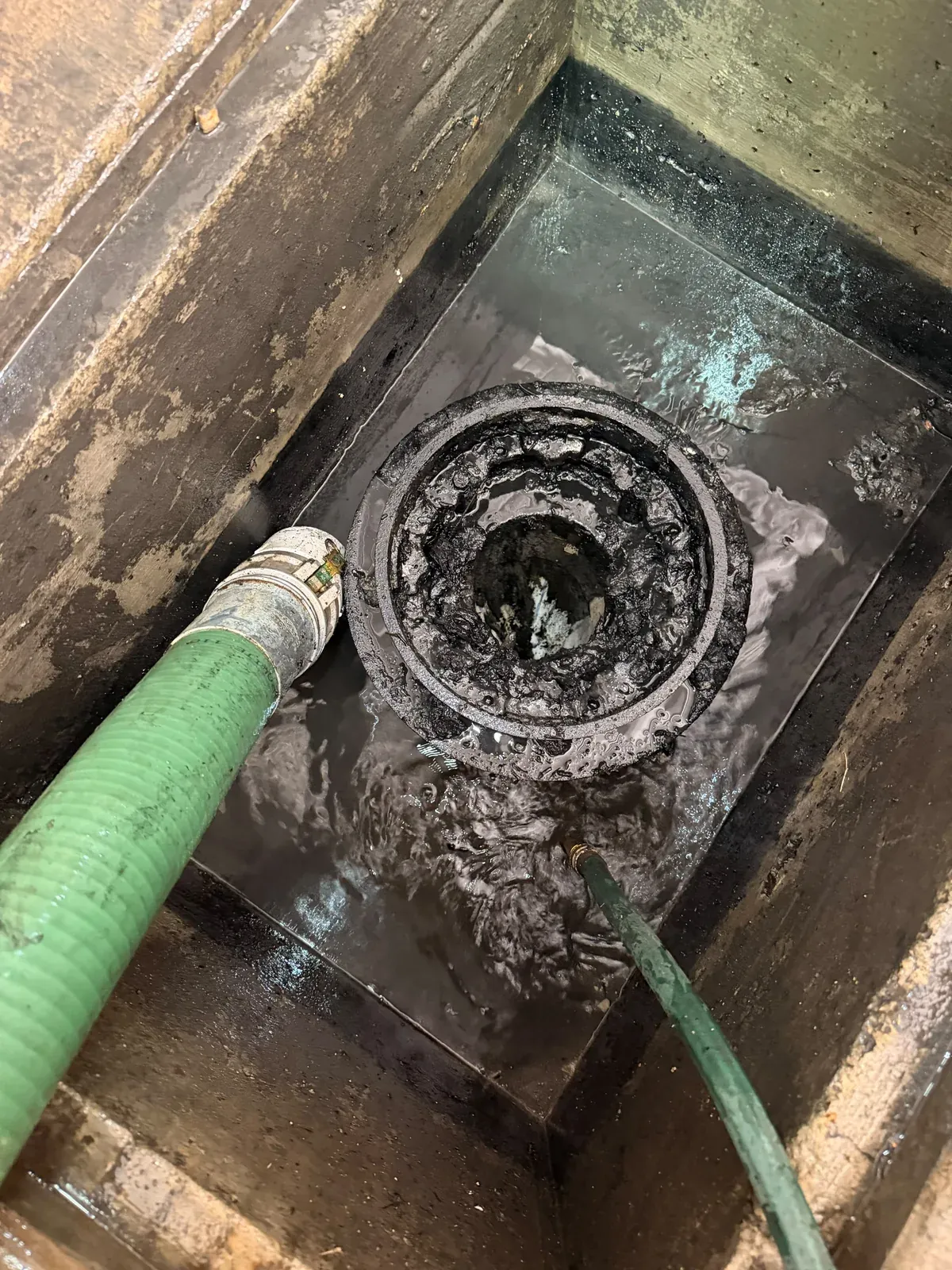 Close-up inside a grease trap showing heavy grease build-up at the outlet baffle